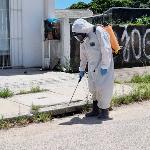 Técnico NOVAECO aplicando produto em calçada e meio-fio — controle de pragas urbanas em área externa
